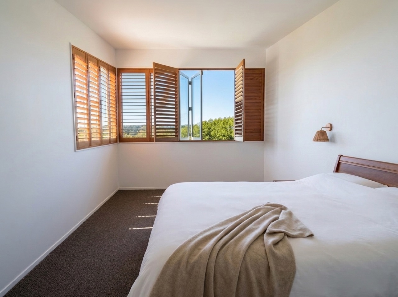 View from the newly upgraded master bed looking through open cedar plantation shutters to the green trees and blue sky
