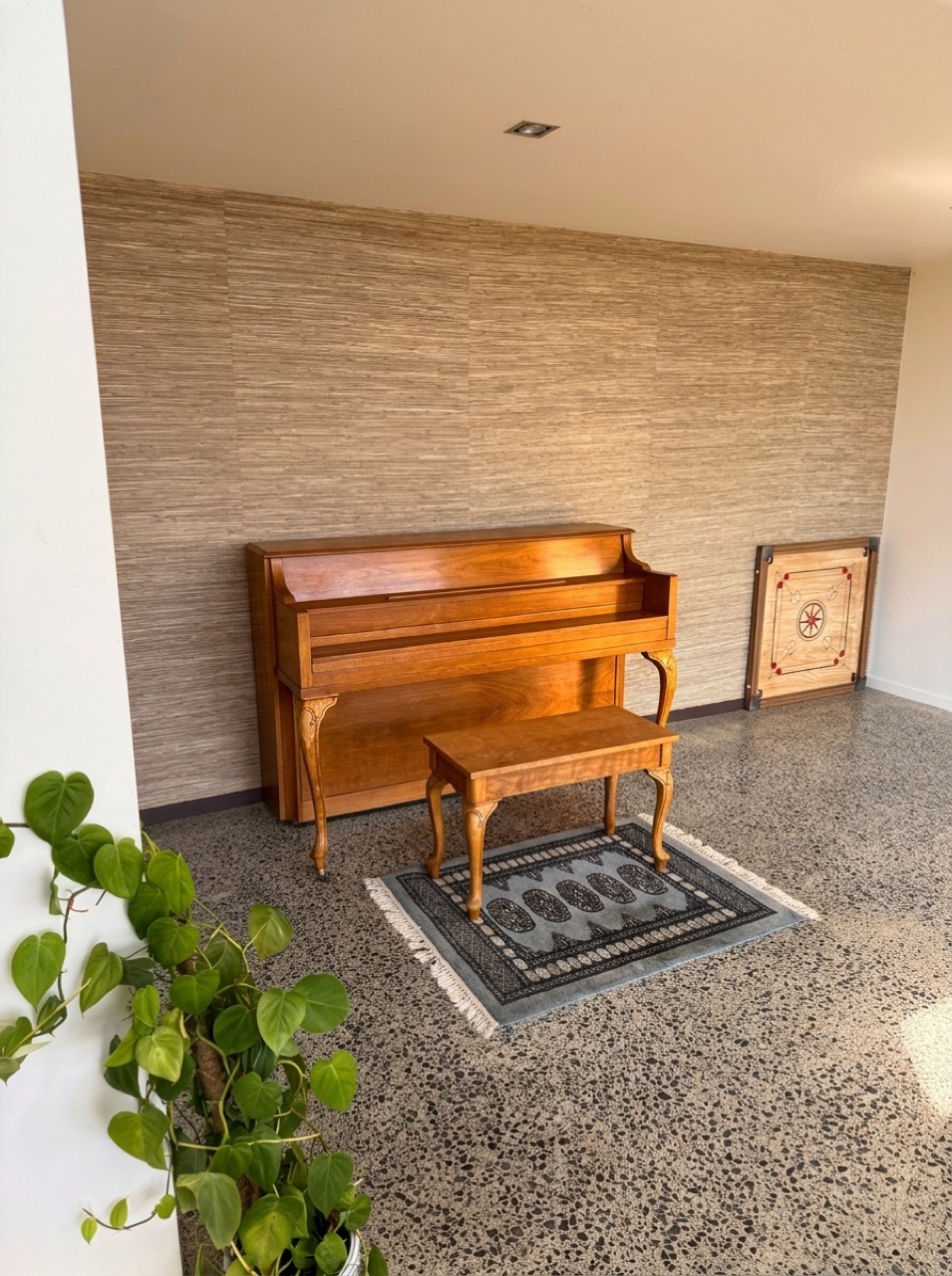 Rich mahogany acoustic upright piano with matching bench and traditional wooden Carrom board